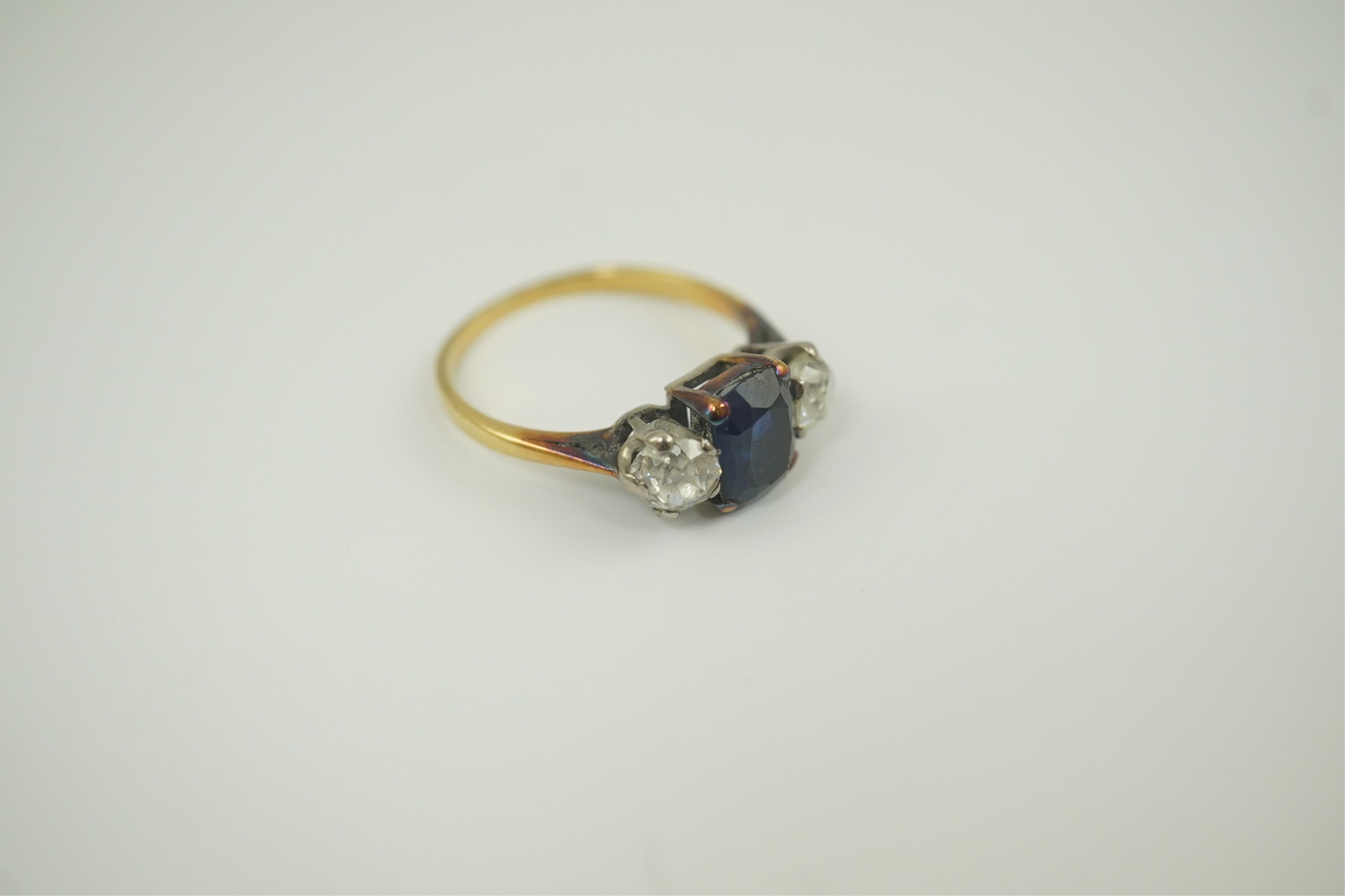 A gold, single stone oval sapphire and two stone round cut diamond set ring